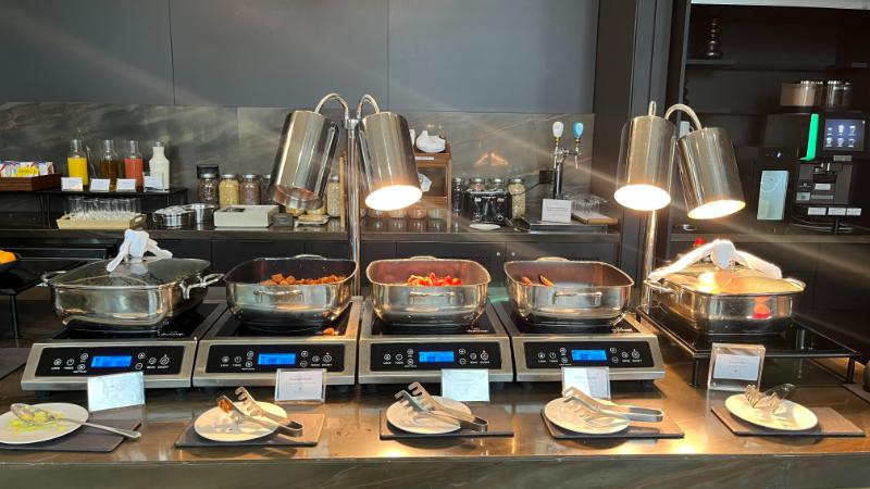 Hot breakfast buffet items served at JW Marriott Executive Lounge, including eggs, sausage, and more.